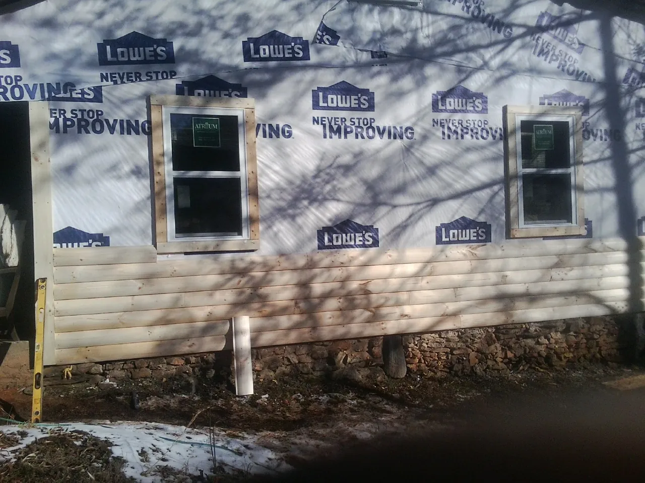 House wrap and new log siding going up on an exterior wall in Idanha
