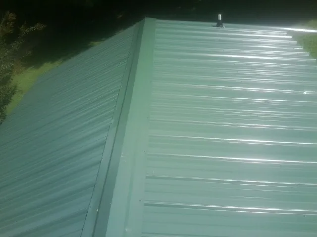 New green metal panels meeting at the ridge of a roof — Flat Roof Repair work by our crew in Idanha