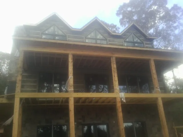 Dormers and porch framing on a large log home under construction — Roof Coating work by our crew in Idanha