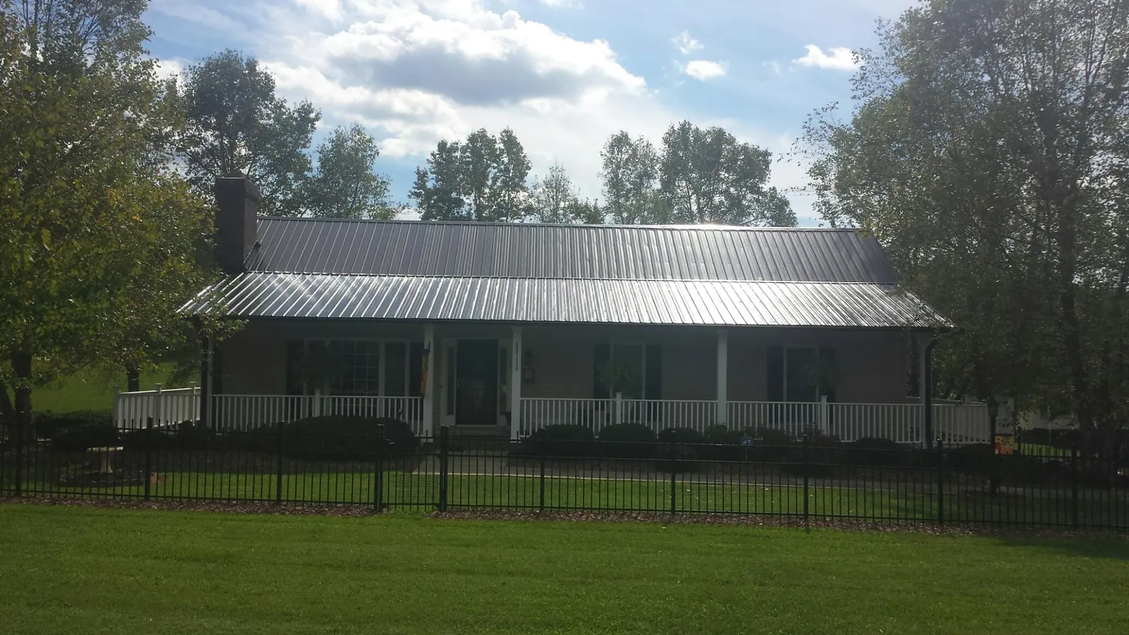 Gray metal roof on a brick ranch with a full width front porch — Gutter Guard Installation work by our crew in Idanha