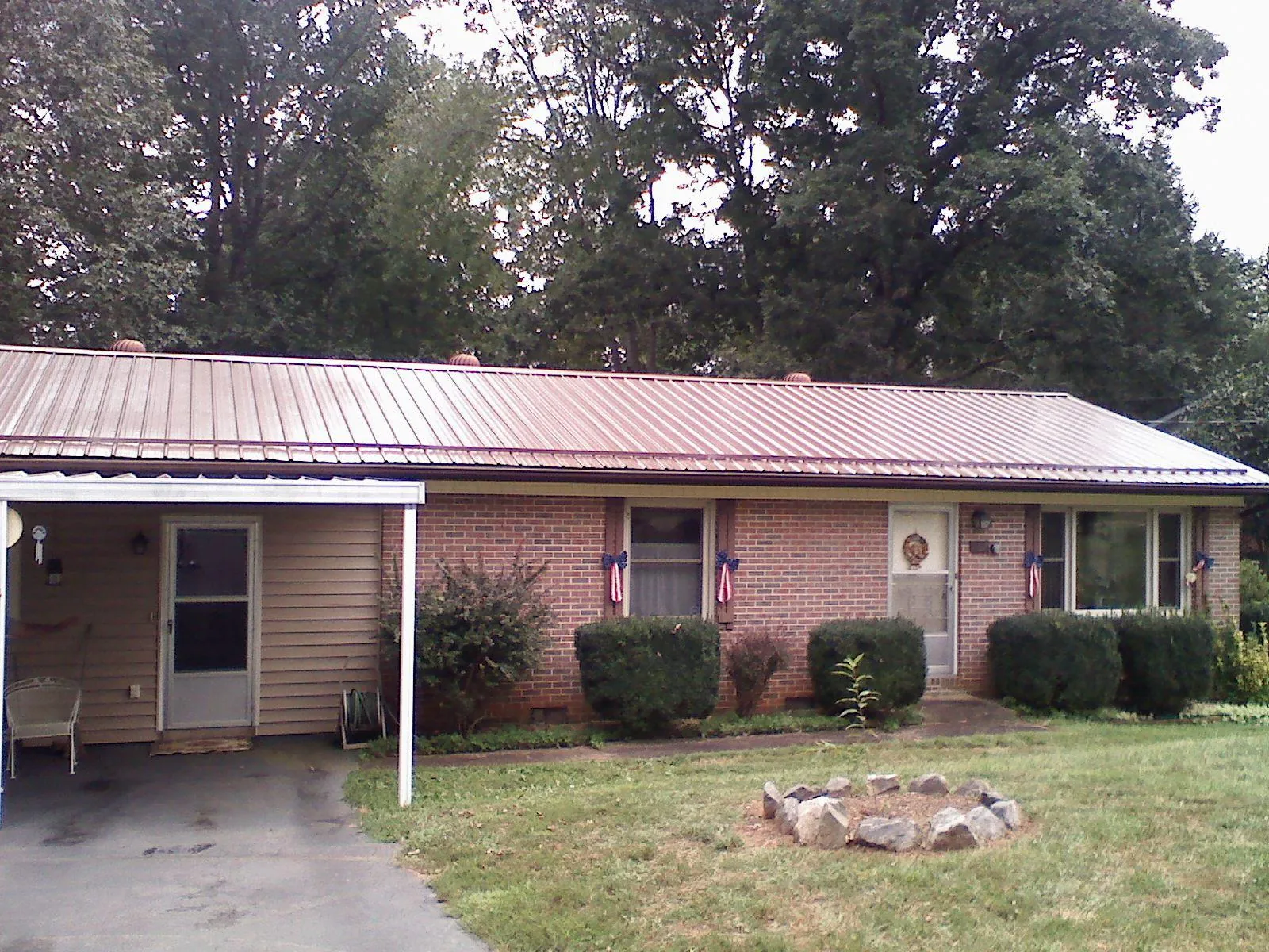Bronze metal roof and carport on a brick ranch home — Roof Repair work by our crew in Idanha