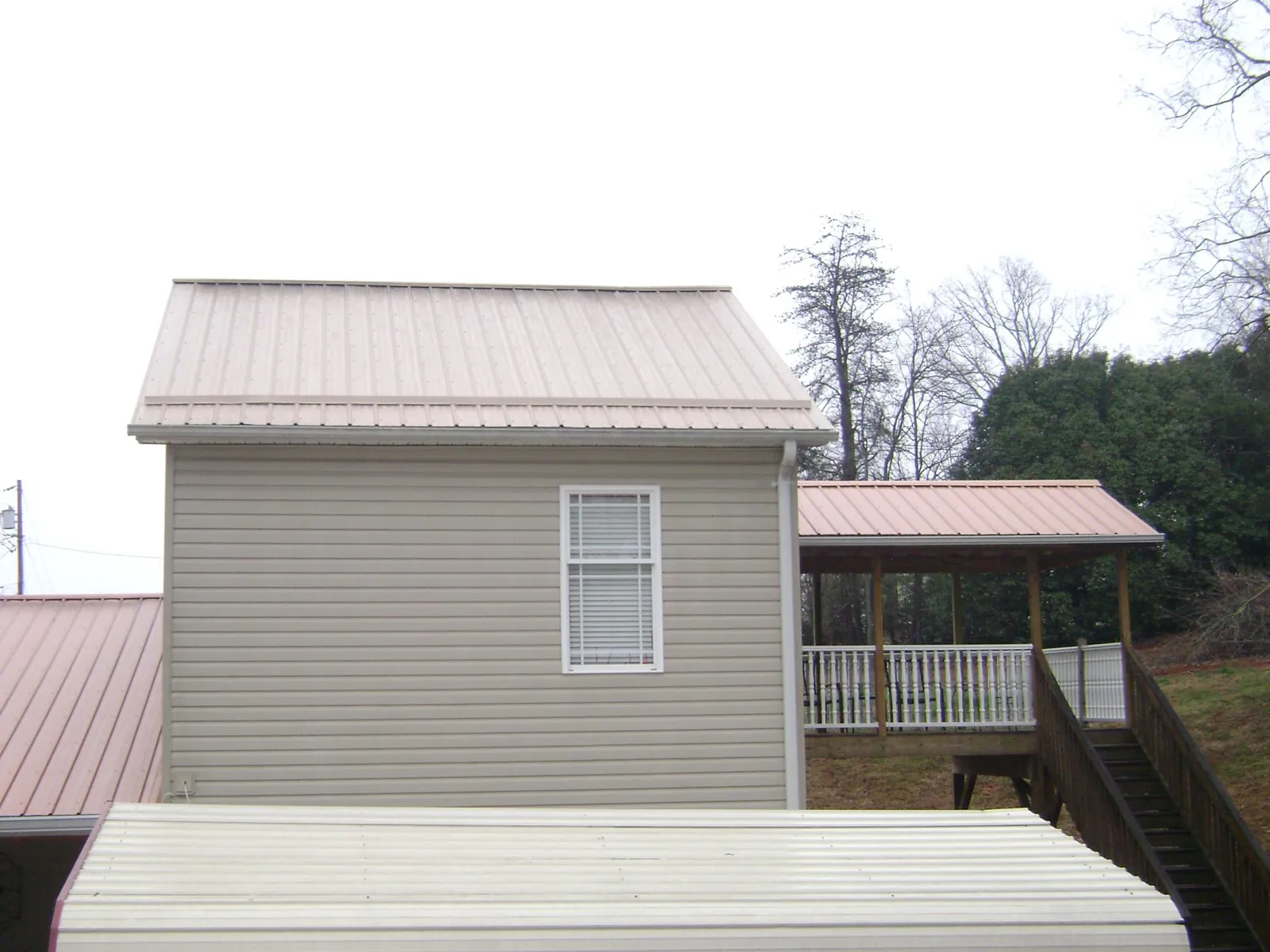 Tan metal roofs on a two story addition and attached porch, from a Roof Replacement job in Idanha