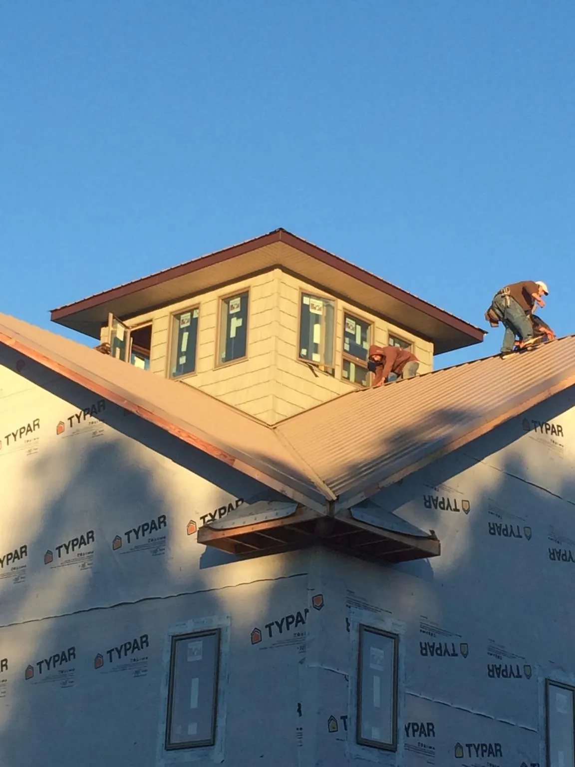 Roofers working around a rooftop cupola on a new metal roof at sunset — Roof Waterproofing in Idanha by Roofing Brothers